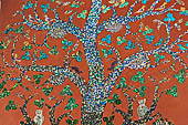 Wat Xieng Thong temple in Luang Prabang, Laos. Detail of the famous tree of life mosaic of the back wall of the sim, in colored glass on a dark red background. 